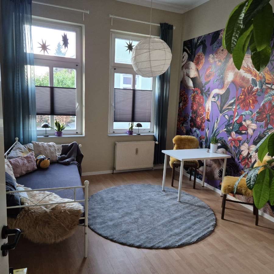 Warmer Praxisraum mit Sofa, rundem Teppich und Blumenwand